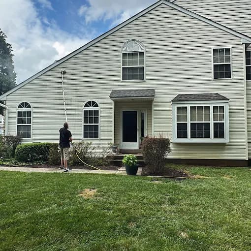 Crew member power-washing a sided home