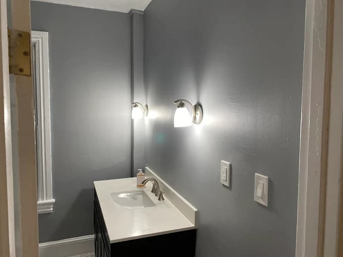 Slate-grey bathroom with white quartz vanity and chrome sconces